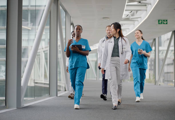 Group, doctor and nurse with tablet for discussion, planning and walking in hospital. Technology, collaboration and diverse team of medical professional people in conversation for healthcare together